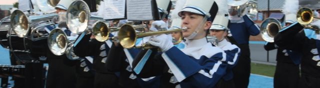 240913 Anthem Members of the Yorktown High School Marching Band Brass Section performing the National Anthem. Students are wearing their YHS uniforms with black pants, Navy, white, black, and light blue tops and white and black hats with white plumes.
