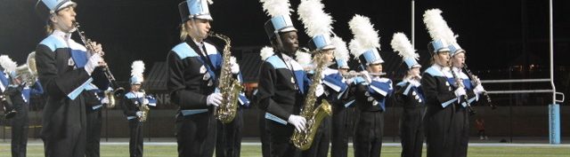 240913 Peft Tenor Alto Members of the Yorktown High School Marching Band Woodwind Section performing the halftime show. Students are wearing their YHS uniforms with black pants, Navy, white, black, and light blue tops and white and black hats with white plumes.